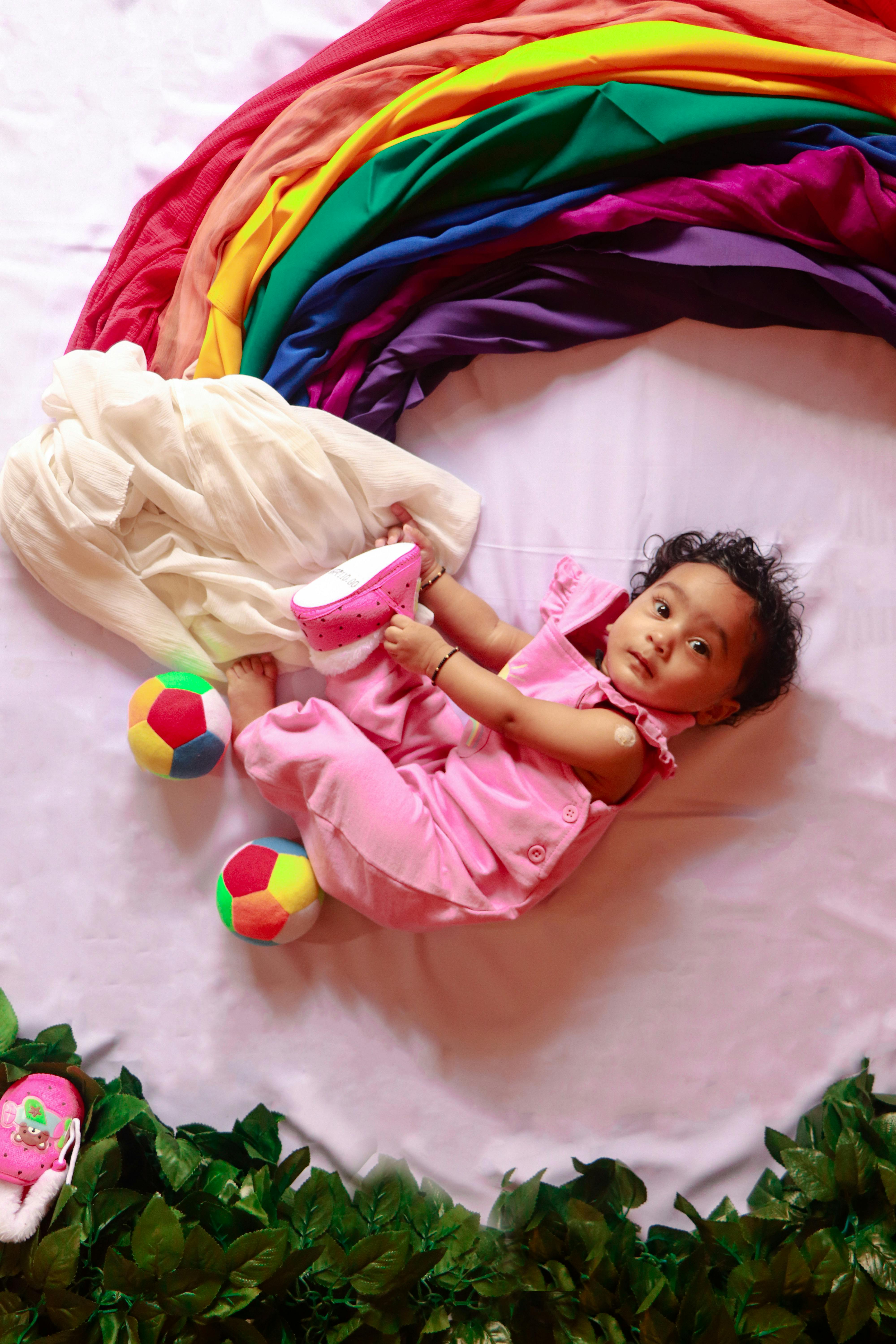Baby lying on a colorful blanket with toys around